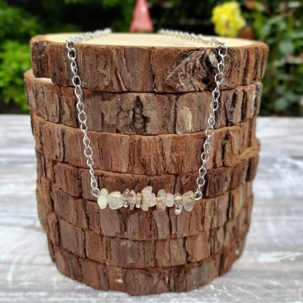 Golden Quartz chip bead bar necklace suspended on stainless steel chain. Necklace shown draped over stack of wood slices.