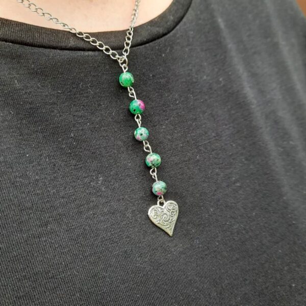 Handmade Ruby Zoisite Necklace with heart charm suspended on stainless steel chain. Shown worn over black slub t-shirt.