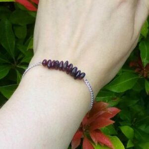 Handmade Garnet Bracelet. This bracelet features a row of Garnet beads on a stainless steel wire which is suspended from a stainless steel chain. Bracelet shown worn on wrist.