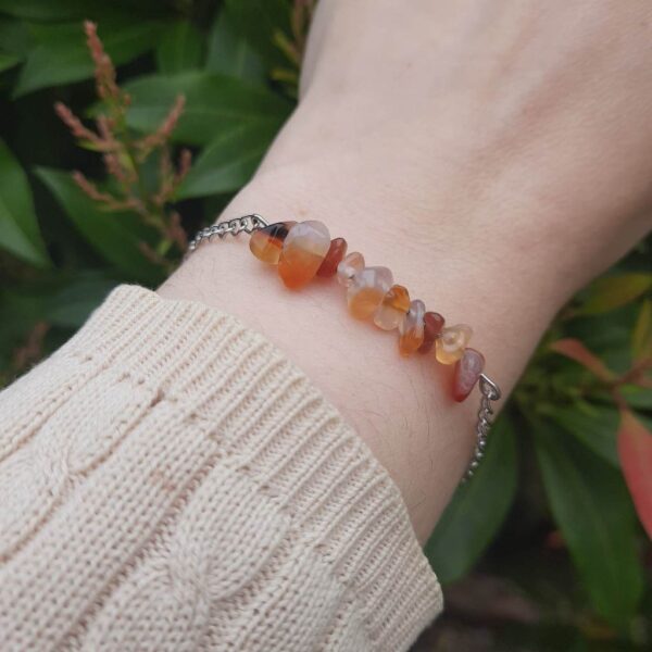 Handmade Carnelian Bracelet. Bracelet features a row of Carnelian chip beads on stainless steel wire suspended from stainless steel chain. Bracelet shown worn on wrist.