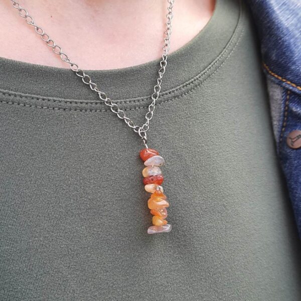 Handmade Carnelian Necklace. Features a row of Carnelian chip beads on stainless steel wire. Suspended from stainless steel curb chain. Necklace shown worn on.